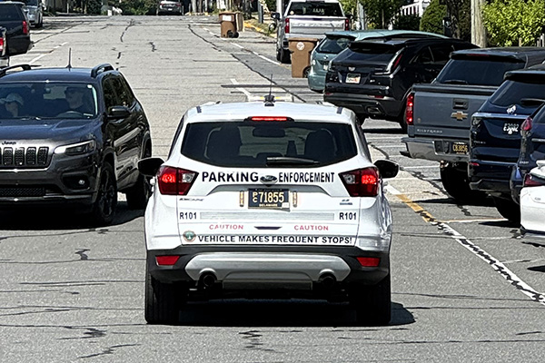 A white parking enforcement vehicle drives along a street.