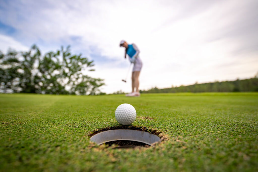 person at golf course putting into hole