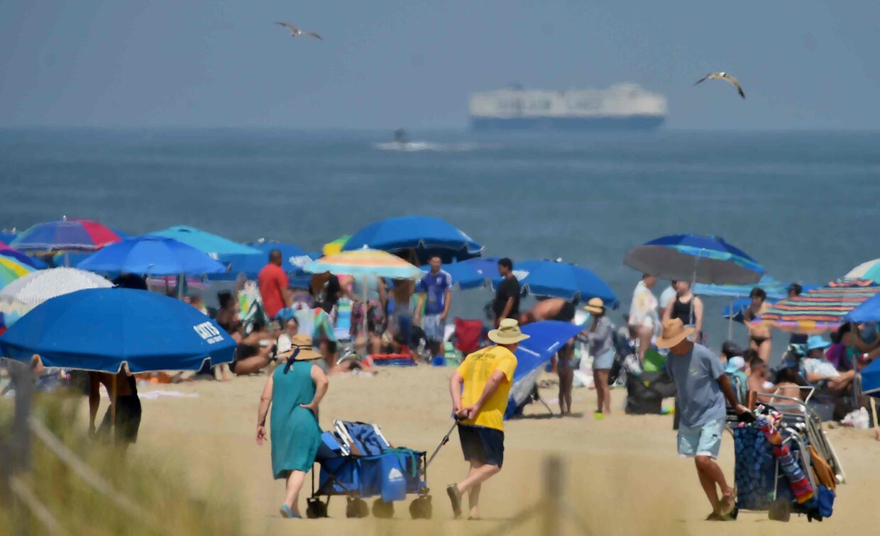 People arriving on the beach; ocean and large ship in background